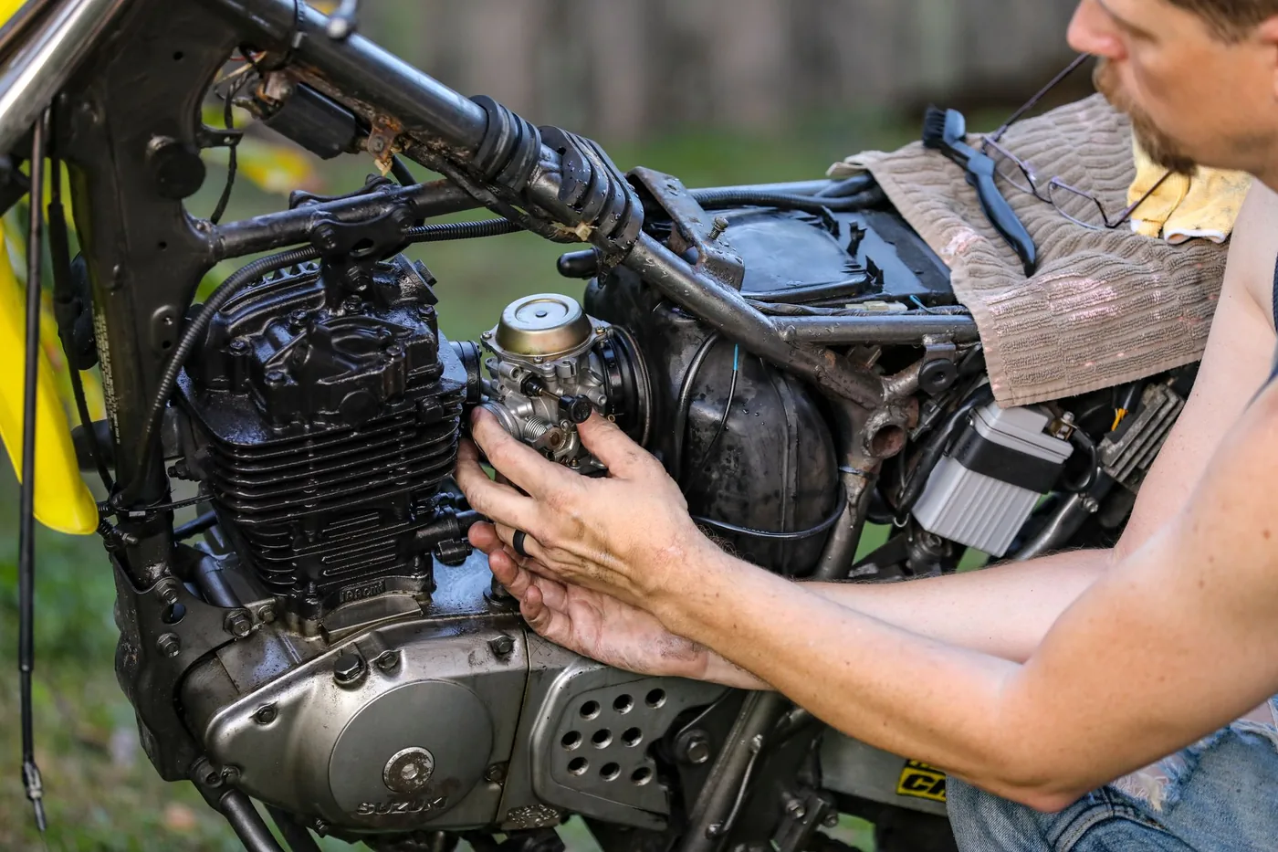 Hands working on a small motorcycle engine