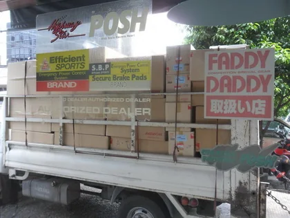 A pickup truck stacked high with boxed parts outside the shop, below POSH and Faddy Daddy authorised-dealer signs.