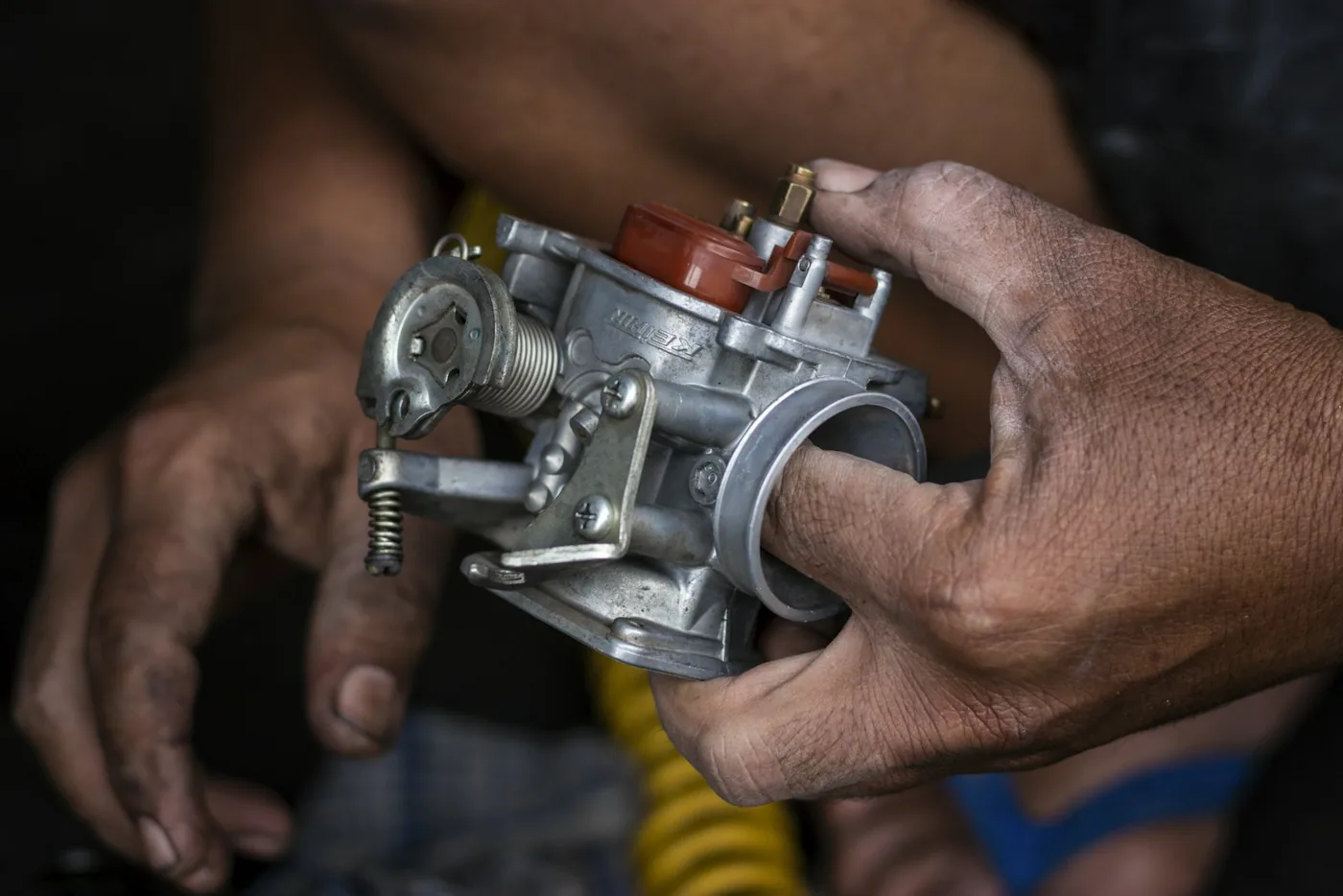 Mechanic holding a motorcycle carburetor