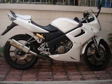 A white Honda CBR150R sports motorcycle photographed side-on against a plain wall.