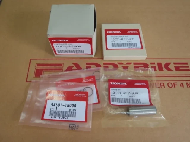Boxed and bagged genuine Honda parts with printed part-number labels, laid out on a Faddybike work mat.