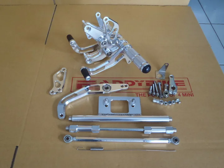 A complete Honda Monkey rearset kit laid out flat: footpeg hangers, brake and gear linkages, mounting plate, connecting rods and fixings.