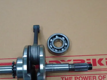 A Honda Wave125 crankshaft assembly with its main bearing and gear, laid out on a Faddybike work mat.