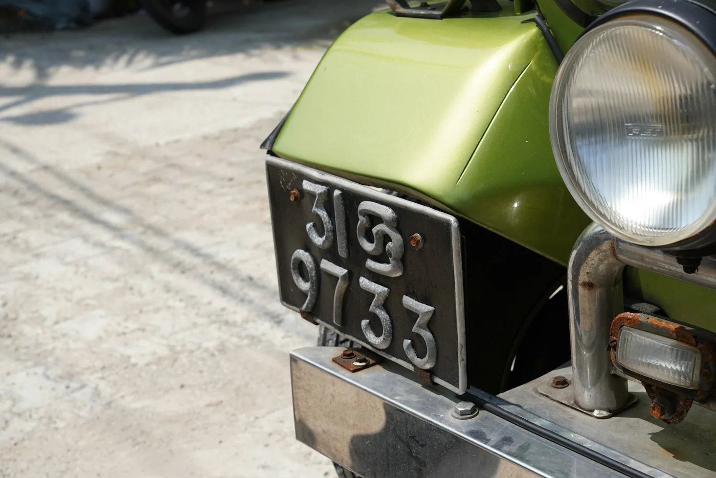 An older motorcycle carrying a metal number plate