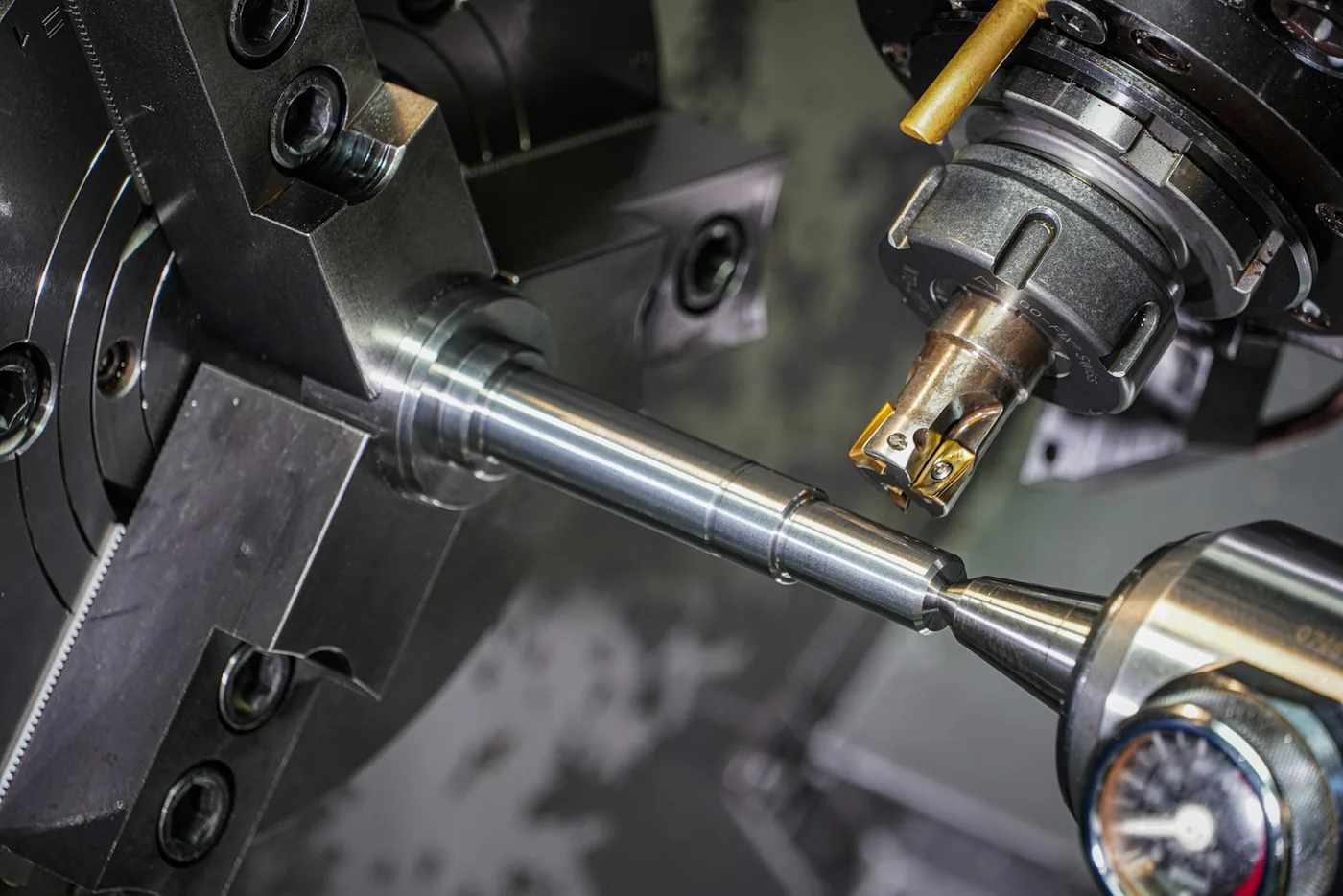 A metal rod held in a lathe chuck being machined by a cutting tool