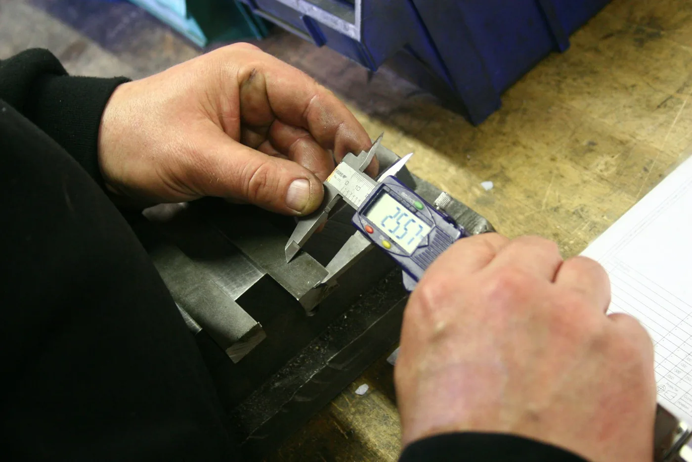 Hands using a digital caliper to measure metal part