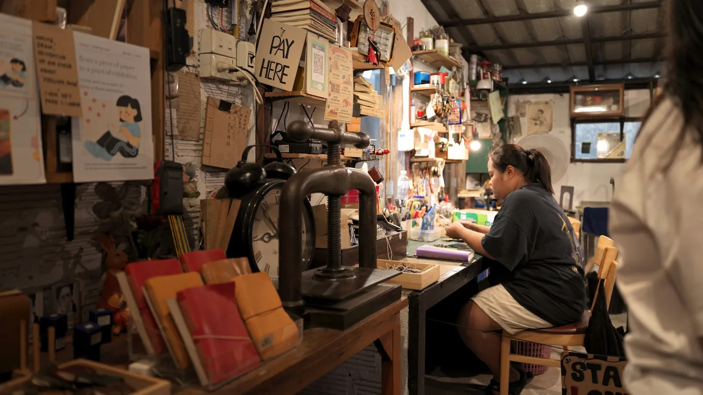 A person working at a desk in a cluttered craft workshop