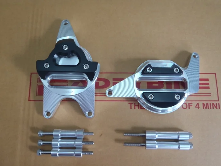 A pair of machined aluminium engine covers with black inserts, laid out on a Faddybike work mat with their mounting bolts and spacers.
