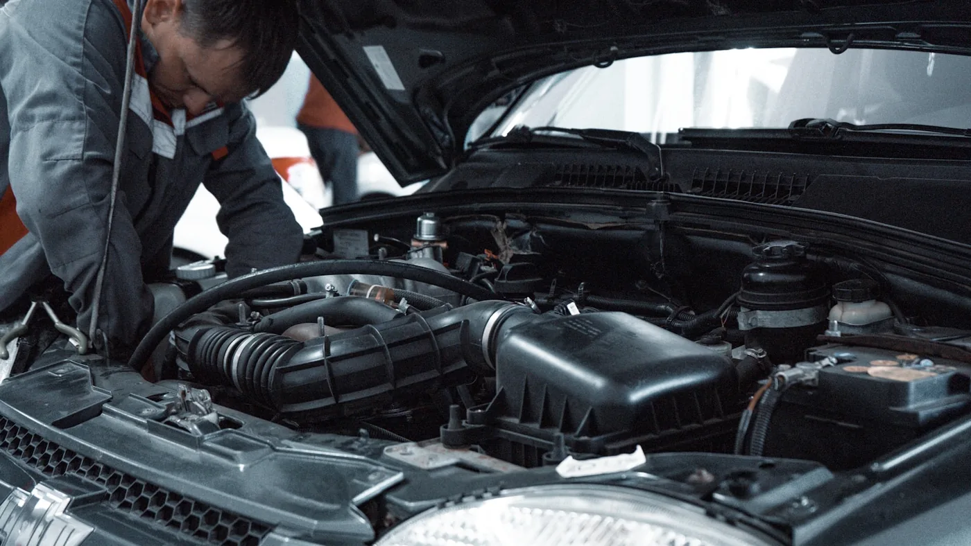 A mechanic in a grey uniform inspecting an engine