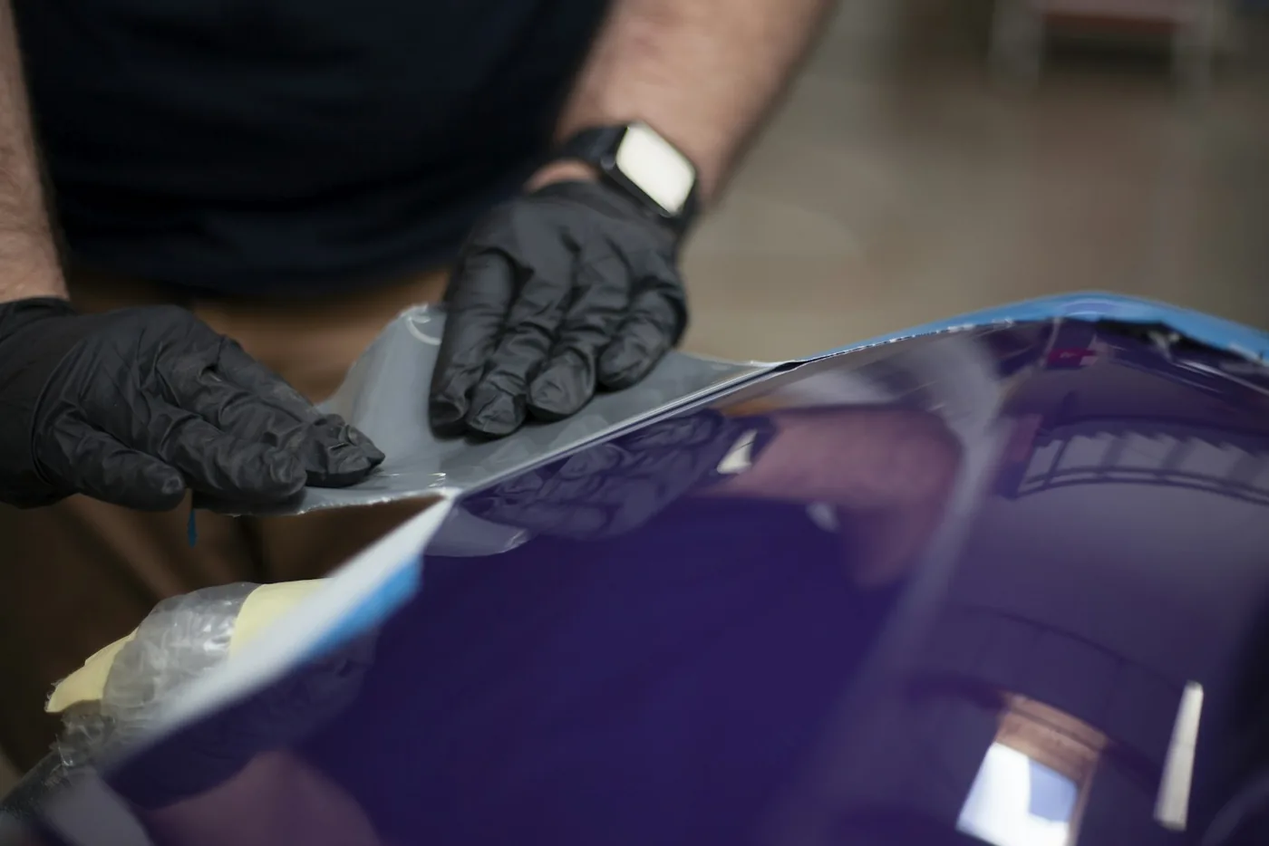 Gloved hands working on a painted body panel