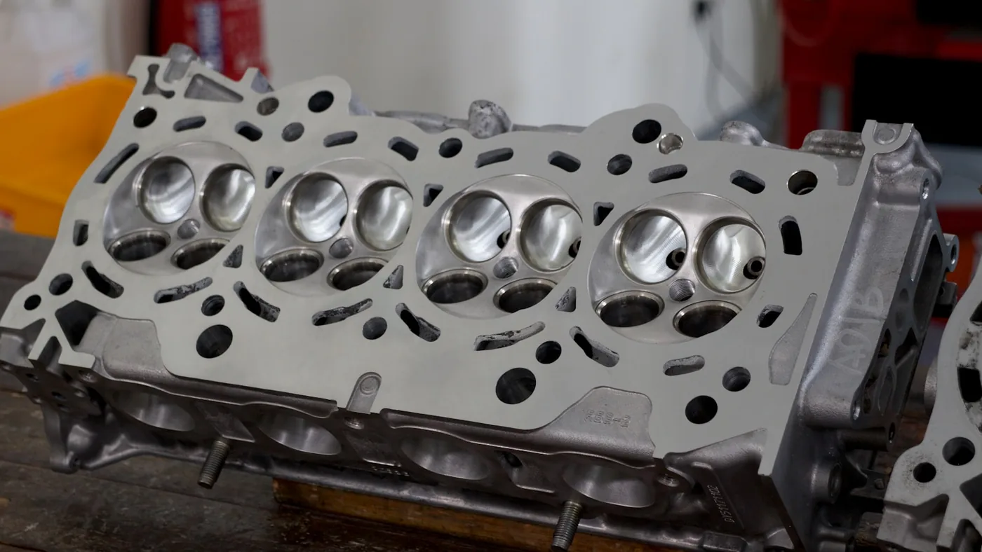 A bare cylinder head resting on a bench