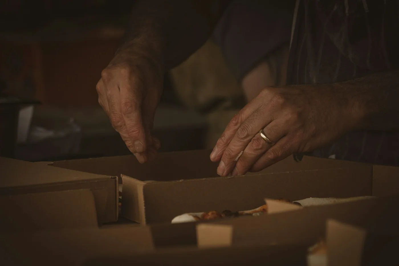 Hands closing a cardboard carton