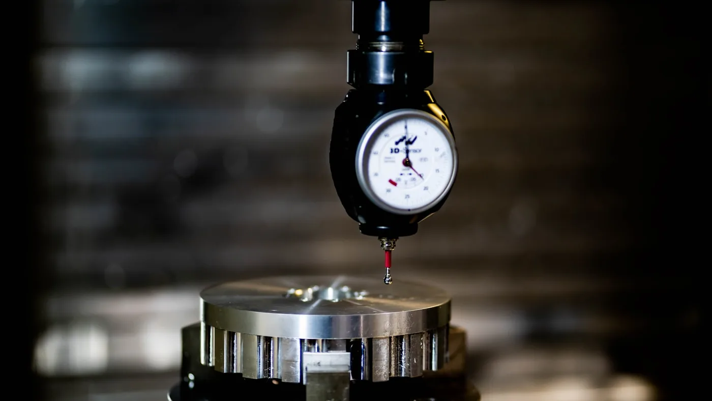 A dial gauge set over a machined part