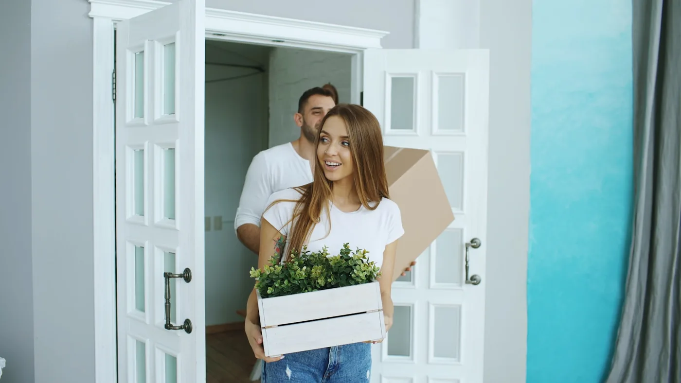 Couple carrying boxes into a new home