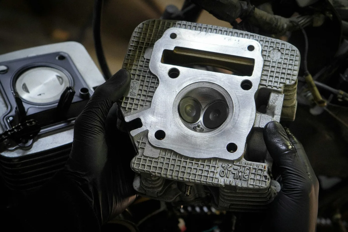 A cylinder head held in gloved hands